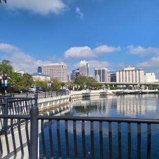 A serene view of the city skyline reflecting on the calm waters under a clear blue sky.