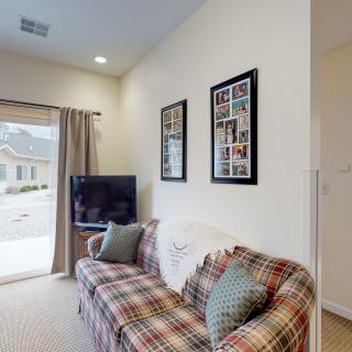 A cozy living room with a plaid sofa and a television, decorated with framed artwork on the wall.