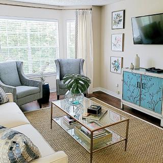 A bright and modern living room featuring comfortable seating, a glass coffee table, and decorative elements.