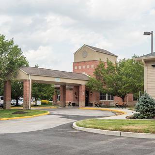 A building with a covered driveway entrance surrounded by trees on a cloudy day.