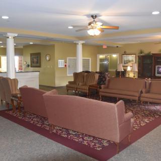 A cozy living room with sofas, a piano, and a ceiling fan.