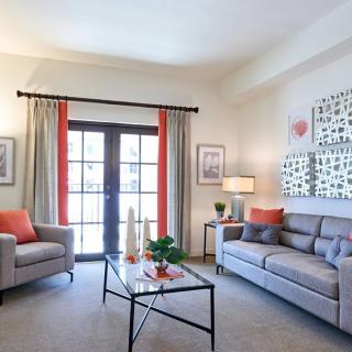 A modern living room with neutral tones and bright accents, featuring comfortable sofas, a stylish coffee table, and decorative wall art.