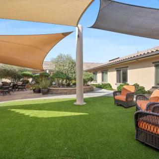 A sunny backyard with shade sails and comfortable patio furniture.