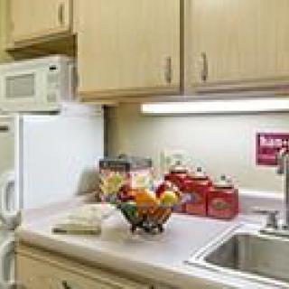 A kitchen counter with a microwave, sink, and fruit bowl.