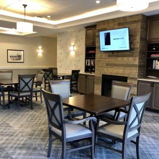 A modern lounge area with tables, chairs, a television, and bookshelves.