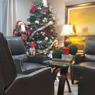 A cozy living room decorated for Christmas with a beautifully adorned tree and comfortable seating.