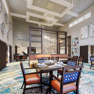 A modern and stylish dining area with elegant chandeliers, artwork on the walls, and comfortable seating.