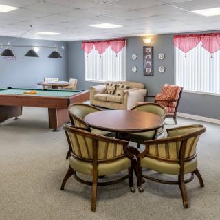 A cozy game room featuring a billiards table and a seating area with comfortable chairs.