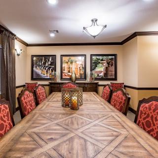 A tastefully decorated dining room featuring a long wooden table surrounded by red upholstered chairs, with framed artwork on the walls.