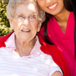 An elderly woman and her caregiver enjoying a sunny day outside.