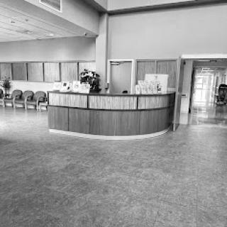 A spacious reception area in black and white, featuring a curved reception desk and empty waiting chairs.