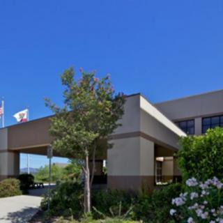A building exterior with flags and trees under a clear blue sky.