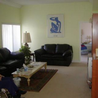 A cozy living room with black sofas, a coffee table, and a minimalist painting on the wall.