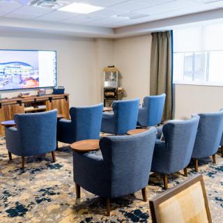 A small conference room with comfortable chairs arranged facing a projector screen.