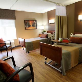 A well-designed patient room in a healthcare facility, featuring two beds and a comfortable seating area.