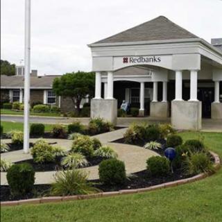 A well-maintained entrance to a facility, featuring landscaped gardens and a flagpole.