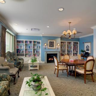 A cozy living room with a library corner, featuring comfortable seating, bookshelves, and a fireplace.