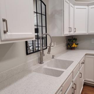 A modern kitchen with white cabinets and countertop.