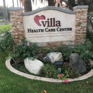 Welcome sign of Villa Health Care Center surrounded by a landscaped garden.