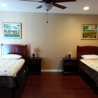 A neatly arranged bedroom featuring twin beds, nightstands, and wall art.
