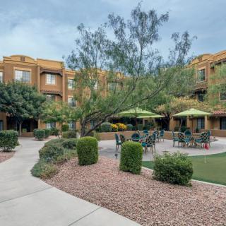 A well-maintained courtyard with outdoor seating and lush landscaping in an apartment complex.
