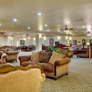 A spacious lounge area with multiple sofas and tables, warmly lit by ceiling lights.