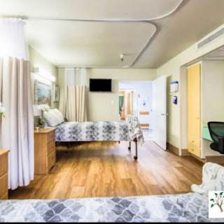 A spacious and well-lit hospital patient room equipped with essential furniture for comfort and care.
