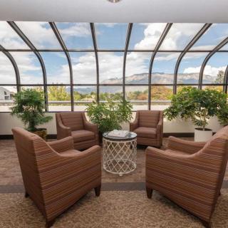A cozy seating area in a glass-enclosed atrium with a scenic sky view.