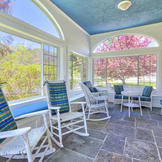 A bright sunroom with rocking chairs and large windows offering a scenic view of blooming trees.
