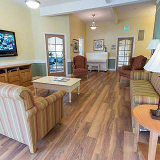 A cozy living room with seating arrangements, a television, and wood flooring.