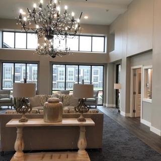 A spacious and elegant living room with a large chandelier and modern furniture.
