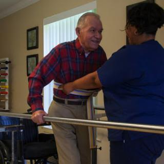 A caregiver assists an elderly man during a physical therapy session, promoting mobility and independence.