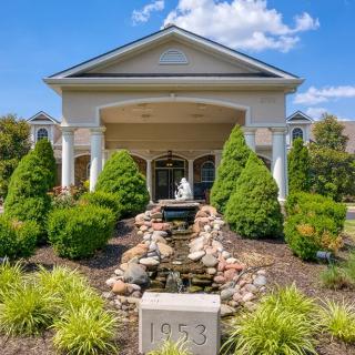 A building entrance with a landscaped garden and fountain in front.