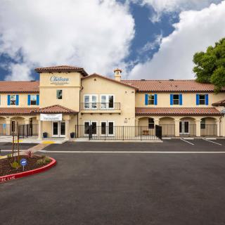 A hotel building with a clear sky backdrop and an empty parking lot in front.