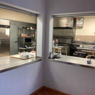 View of a commercial kitchen with stainless steel appliances and open service windows.