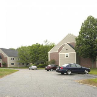 A quiet residential area with parked cars in front of apartment buildings.