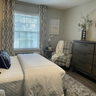 A cozy bedroom with elegant decor, featuring a large bed, a dresser, and a comfortable chair by the window.