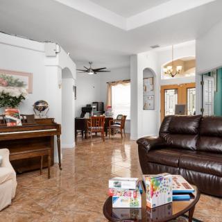 A spacious living room with leather seating, a piano, and elegant decor.