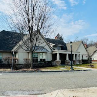 A beautiful suburban house with a welcoming entrance and a tree in front, set against a cloudy sky.