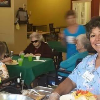 A caregiver assists elderly residents during meal time at a nursing home.