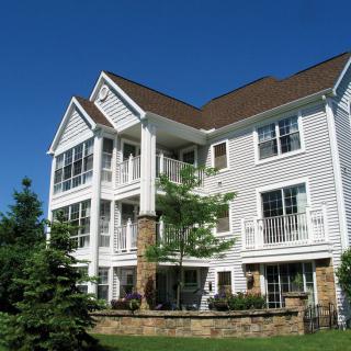 A modern multi-story apartment building with balconies and a well-maintained lawn.