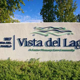 Entrance sign for Vista del Lago community surrounded by greenery.