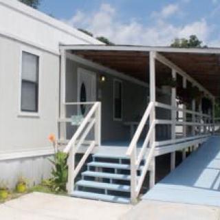 A mobile home with a covered porch and a ramp leading up to the entrance.