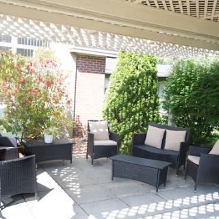A cozy outdoor patio area featuring modern seating and lush greenery.