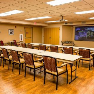 A conference room with arranged tables and chairs, featuring a projector screen.