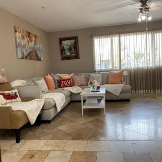 A cozy living room with a sectional sofa, colorful pillows, and wall art.