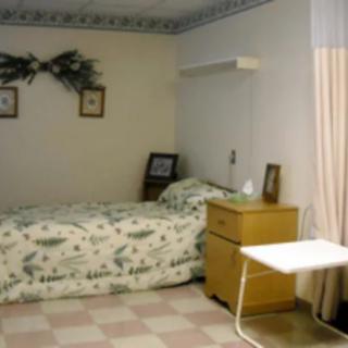 A simple hospital-style bedroom with a single bed and nightstand.
