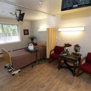 A hospital room with a patient bed, seating area, and TV.