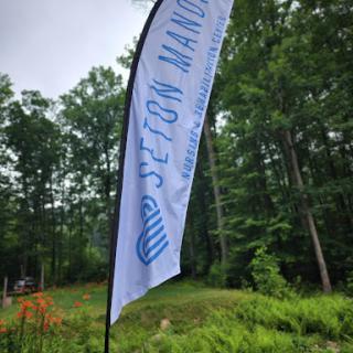 A flag displaying 'Seton Manor' stands tall amidst a lush green background.