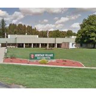 A school building with a sign reading 'Riverside Village School' in front of a grassy area.